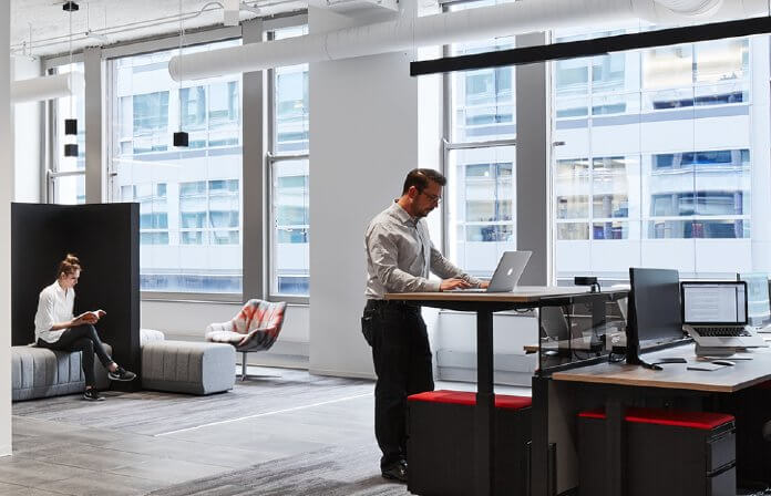 Man standing at desk, working on laptop